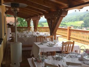 a restaurant with white tables and chairs and a balcony at Selský Dvůr Perštejn in Perštejn