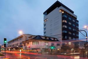 Un edificio alto en una calle de la ciudad por la noche. en abba Presidente Suites Puerto Montt, en Puerto Montt