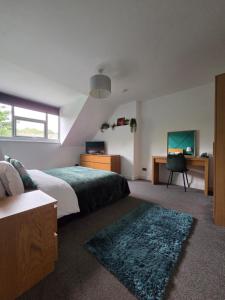 a bedroom with two beds and a desk and a television at Modern Spacious Apartment Steps from City Centre in Norwich