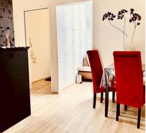 パーダーボルンにある3 Ferienwohnungen in stadt Paderbornのダイニングルーム(テーブル、赤い椅子2脚付)