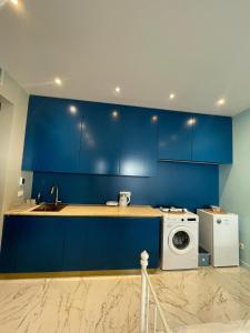 a kitchen with blue cabinets and a washing machine at KAI Condo 3 Min Walking to Beach in Donja Lastva