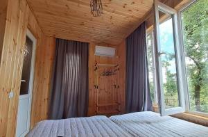 a bedroom with a bed in a room with windows at Villa Lematue Guest House in Jvari