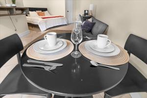 a black dining room table with plates and silverware at Modern Studio Apartment near Merrimack Park in Huntsville +30 photos