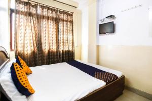 a bedroom with a bed and a window with a television at SPOT ON Standard in Jabalpur