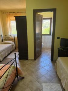 a room with two beds and a bathroom with a television at Agriturismo Montealma in Nulvi