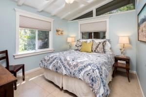 a bedroom with a bed and two windows at Mid-century Modern In Enchanting Desert Garden in La Quinta