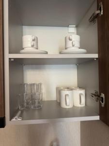 a shelf with cups and glasses in a bathroom at Bakuriani Crystal Loft Apt in Bakuriani