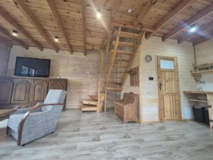 a living room with a couch and a tv and wooden walls at Odpocznij u Ani in Szypliszki