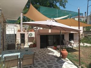 a patio with an umbrella and a table and chairs at The cave of Cyclops in Mákri +11 photos