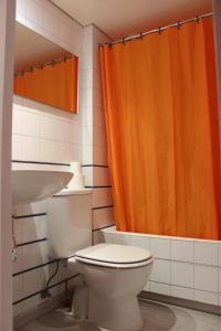 a bathroom with a toilet and an orange shower curtain at Hostal Cristina in Cadaqués
