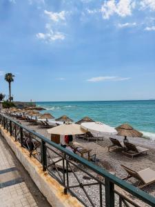 a beach with chairs and umbrellas and the ocean at Aphrodite Apartment in Athens