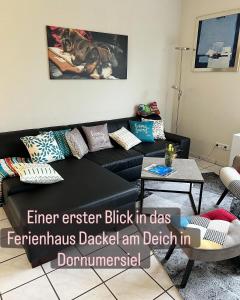 a black leather couch in a living room at Ferienhaus Dackel am Deich - strandnah - eingezäunter Garten - Ruhe in Dornum +2 photos