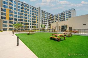 une cour avec des tables de pique-nique devant un bâtiment dans l'établissement Chic Liva 1br Family-friendly Great Amenities, à Nadd Shubayḩ