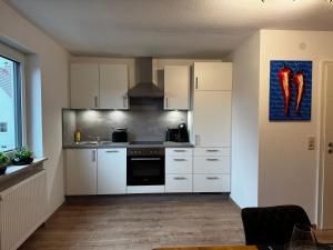 クルムバハにあるSchöne NEU Renovierte Ferienwohnungのキッチン(白いキャビネット、コンロ付)