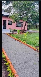 una pasarela frente a un edificio rosa con plantas en Eropia peaceful home in arusha Town, KIjenge & Njiro, en Arusha
