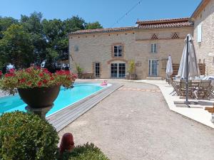 a woman sitting in front of a house with a pool at La chambre de Marin in Lombers