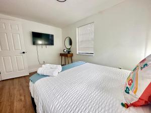 a bedroom with a white bed and a television at Casita-stylish Garden Home 5 Min To Bayshore Water in Tampa