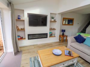 a living room with a couch and a tv at Lavender Cottage in Chathill
