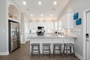 a kitchen with white cabinets and a island with bar stools at Blue Water Escape in Bolivar Peninsula