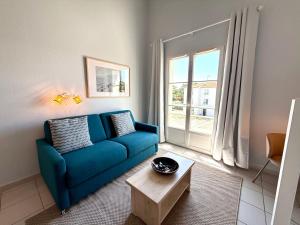 a living room with a blue couch and a table at Le Nid d'Antioche in Ars-en-Ré