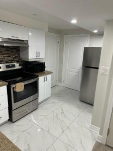 a kitchen with white cabinets and a stove and refrigerator at Cozy 1 Bedroom Apartment in Brampton