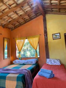 two beds in a room with a window at Chalé Inhambu Tiradentes in Tiradentes