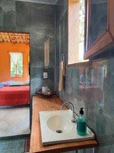 a bathroom with a sink and a room with a bed at Chalé Inhambu Tiradentes in Tiradentes