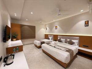 a hotel room with two beds and a tv at Hotel vimlayatan in Ujjain