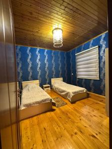 two beds in a room with blue walls and wooden floors at Əşlə günlük ev in Lankaran