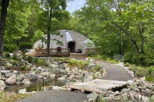 a large building with a bridge next to a river at Dome Compound with Hot Tub, Piano and Rock-Climbing Gym in New Paltz