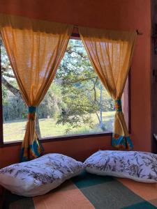 a bedroom with two pillows and a window at Chalé Inhambu Tiradentes in Tiradentes +13 photos