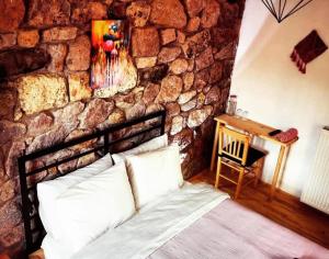 a bedroom with a stone wall with a bed and a desk at Teora taş otel in Hüseyinçakı