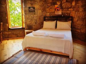 a bedroom with a bed in a stone wall at Teora taş otel in Hüseyinçakı