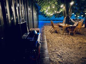 a wooden deck with a table and chairs and a tree at Łąka MOO agroturystyka nad jeziorem, jacuzzi in Lgiń