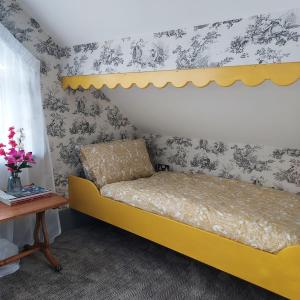 Una cama amarilla en una habitación con un estante. en Apple Blossom Cottage, en New Ross