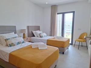 a hotel room with two beds and a window at Edifício da Vinha - Ocean Breeze Apartments in Armação de Pêra