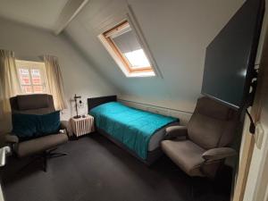 a small room with a bed and two chairs at Ut ânker fan de Jong in Hollum