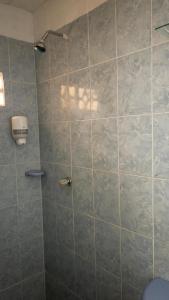 een badkamer met een douche en een betegelde muur bij Hostal El Amanecer Costero in Santa Marta