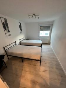 two beds in a room with a wooden floor at Monteurwohnung mit Balkon und 4-Zimmern in Pforzheim