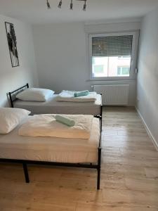 three beds in a room with a window at Monteurwohnung mit Balkon und 4-Zimmern in Pforzheim