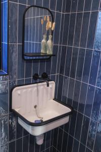 a sink in a blue tiled bathroom with a mirror at The Botháns in Articlave