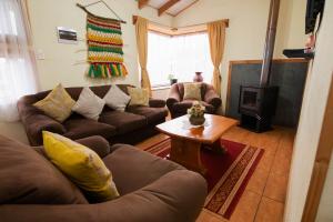 a living room with two couches and a table at Cabañas El Portal in Neltume