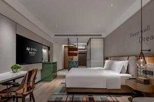 a bedroom with a large white bed and a desk at EVEN Hotel Yining in Yining