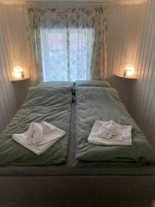 a bed with two towels on it with a window at Nydelig sentrumsleilighet in Arendal