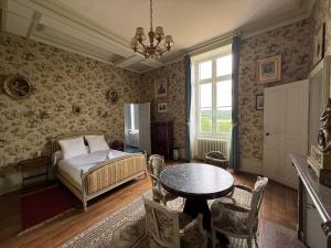 una camera da letto con un letto, un tavolo e delle sedie di Chateau de Resteau Haut de Gamme 15 pers a Maigné