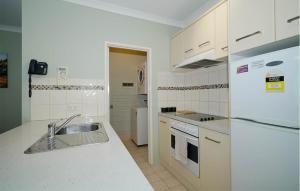 a white kitchen with a sink and a refrigerator at 40 Modern & Chic Apt In East Perth in Perth