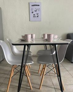 Una mesa con sillas y tazas encima. en Casa amplia y cómoda, en Nueva San Salvador