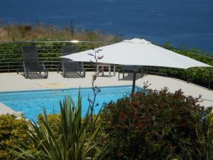 a white umbrella sitting next to a swimming pool at Résidence Pietri in Calcatoggio