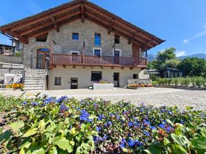 a building with a balcony and flowers in front of it at Le Grenier d'Antan - Relax Suite Aosta in Aosta