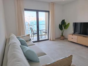 a living room with a couch and a television at Edifício da Vinha - Ocean Breeze Apartments in Armação de Pêra